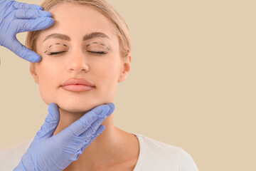 Young woman with marks on her eyes and plastic surgeon against beige background, closeup....