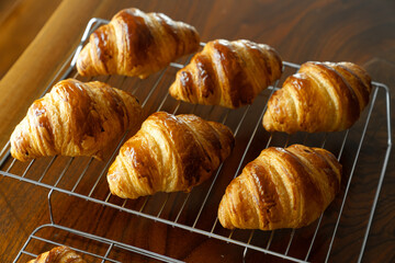 金網に並べたたくさんの焼き立てクロワッサン　木製テーブルの背景