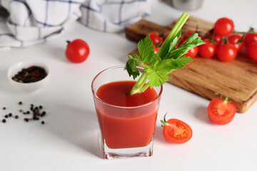 Glass of bloody mary with celery and tomatoes on light background