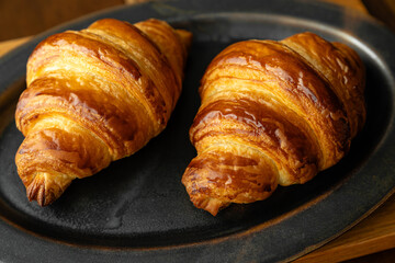 黒い皿に乗せた焼き立てクロワッサン　木製テーブルの背景