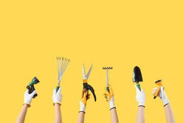 Female hands with gardening tools on yellow background