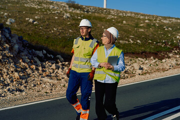 Muslim Female Engineer and Her Male Colleague Reviewing Work on Wind Turbines.