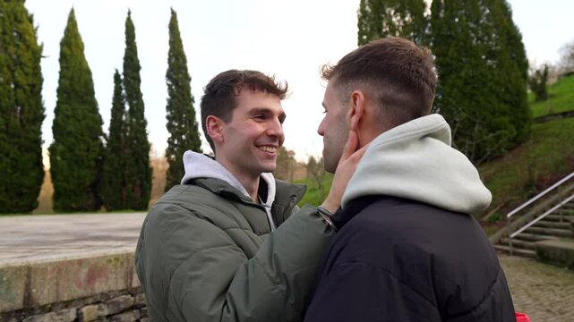 Intimate gay couple sharing tender moments, exchanging loving gazes and gentle touches in urban park setting, expressing deep connection and affection