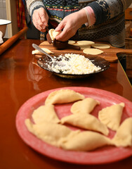 Woman skillfully fills dough circles with cheese in a warm kitchen.