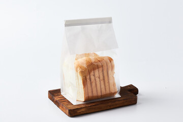 Sliced Bread in a Sealed Bag on a Wooden Cutting Board in a Bright Setting
