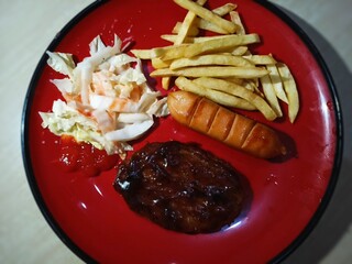 Beef, sausage, potatoes and vegetables are served on a plate