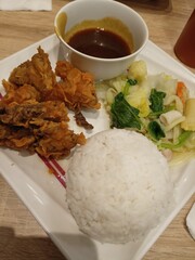 Rice, meat and vegetables are served on a white plate