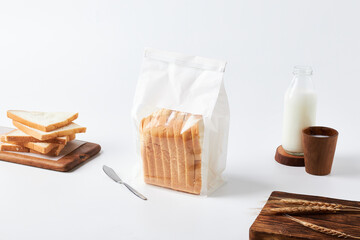 Sliced Bread Package With Fresh Slices, Milk, and Wooden Serving Board Arranged on a Clean Tabletop
