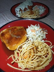 spaghetti and meat and salad are served on plates