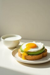 Sunny-side up egg and avocado toast breakfast on a plate with a bowl of milk