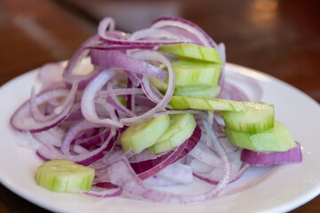 Fresh salad with onions and cucumbers on plate.