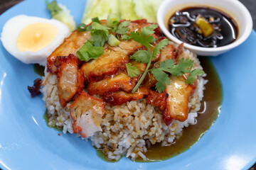 Sliced BBQ red pork over rice with hard boiled egg top with red sweet sauce .