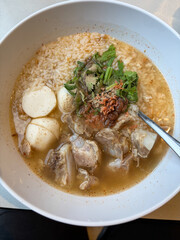A bowl of rice soup with pork meat.
