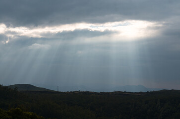 Sun rays cutting through the clouds with the mountains in the background