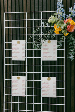 Elegant seating chart display with flowers at a modern outdoor event in the afternoon