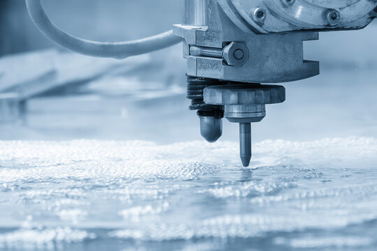 The abrasive waterjet cutting machine cutting the metal plate in the light blue scene.