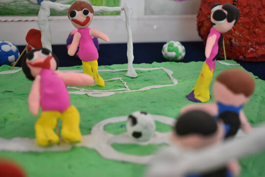 Clay figures playing soccer on green field with goalpost in playful and colorful setting