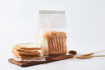 Sliced Bread in a Plastic Bag on a Wooden Cutting Board With Wheat