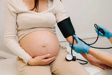 Gynecologist measures blood pressure for pregnant patient in the maternity center. High pressure...