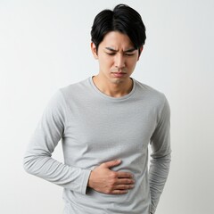 Obraz premium young man having stomach ache with hand holding stomach affected by diarrhea, or internal disease. wearing a plain t-shirt