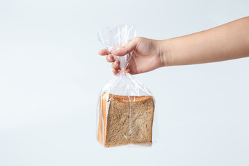 Hand Holding a Plastic Bag With Loaf of Sliced Bread Against a Plain Background