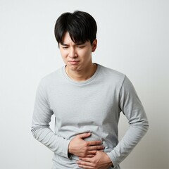 young man having stomach ache with hand holding stomach affected by diarrhea, or internal disease. wearing a plain t-shirt