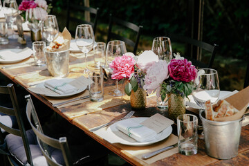 Elegant outdoor dining setup adorned with flowers and glassware in a serene garden setting at midday