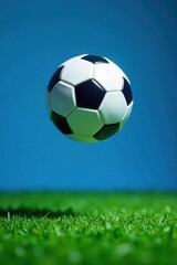 Fototapeta premium Football ball suspended in mid-air within the cut-out of a football field on blue background, field, arena, sports