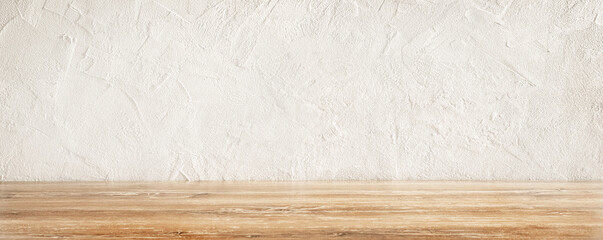 Rustic wooden table surface with a textured white wall background in a well-lit kitchen.