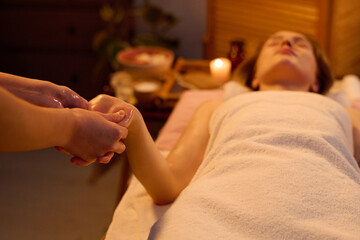 Medium close up of unrecognizable masseuse massaging with lotion female hand