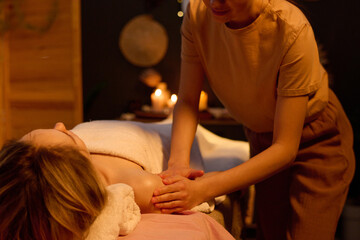 Medium close up of unrecognizable masseuse kneading female body to reduce her from delayed onset...
