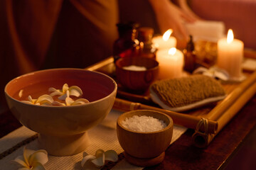 Medium close up of ceramic bowl with pure water and floating plumeria buds, tiny wooden bowl with sea salt