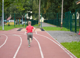 Obraz premium Attractive Caucasian boy runs around the stadium