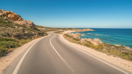 Coastal Road Winding Along Rocky Shoreline Under Bright Blue Sky