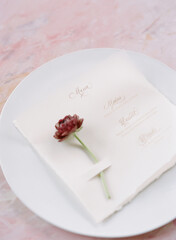 Elegant wedding invitation with a floral accent on a decorative plate in a soft romantic setting