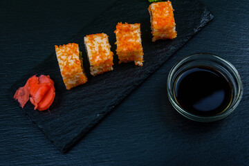 Sushi roll philadelphia with salmon, rice, cheese, cucumber, avocado and caviar on a slate board. Japanese food