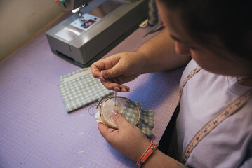 Seamstress embroidering fabric with needle and thread in workshop