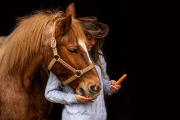 Happy equestrian: A young teenager girl and her horse interacting together in front of black...