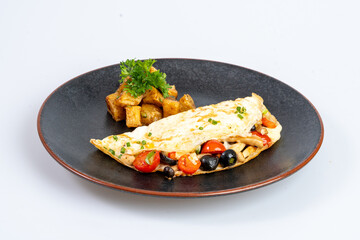 Delicious omelette with vegetables and roasted potatoes, garnished with herbs, served on black plate, showcasing vibrant and appetizing meal