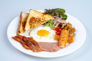 Delicious breakfast plate featuring toast, fried egg, bacon, sausage, and vegetables, perfect for hearty meal to start day