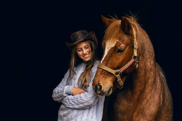 Best friends: A young teenager girl interacting and cuddle with her brown horse in front of black...