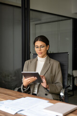 Vertical portrait of young latin professional business woman working on tab pc computer. Middle...