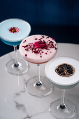 Colorful cocktails with floral garnishes on marble table