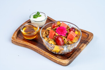 Fresh fruit salad with granola, honey, and yogurt served on wooden tray. vibrant colors and textures create delightful and healthy meal option