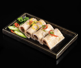 Deliciously presented sushi rolls with fresh vegetables, garnished with colorful peppers and herbs, served on sleek black plate
