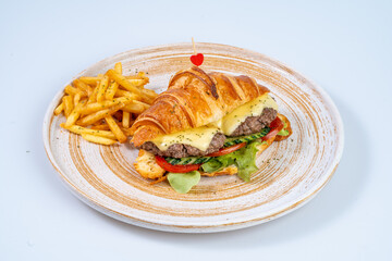 Delicious croissant sandwich with beef patty, cheese, and fresh vegetables, served with crispy fries. perfect meal for any time of day