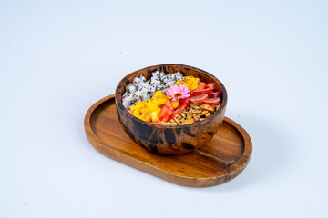 vibrant fruit bowl featuring dragon fruit, mango, and watermelon, garnished with flower and granola, served in wooden bowl on wooden tray