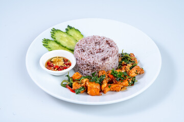 Delicious plate of rice with chicken, herbs, and dipping sauce, garnished with cucumber slices. vibrant and flavorful meal