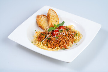 Delicious spaghetti bolognese served with garlic bread and fresh basil, showcasing rich meat sauce and topped with grated cheese. Perfect for pasta lovers