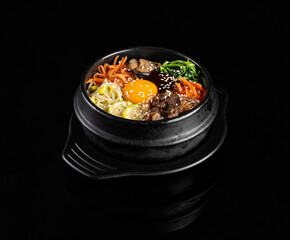 Delicious bibimbap served in traditional stone bowl, featuring colorful vegetables, beef, and sunny side up egg, garnished with sesame seeds
